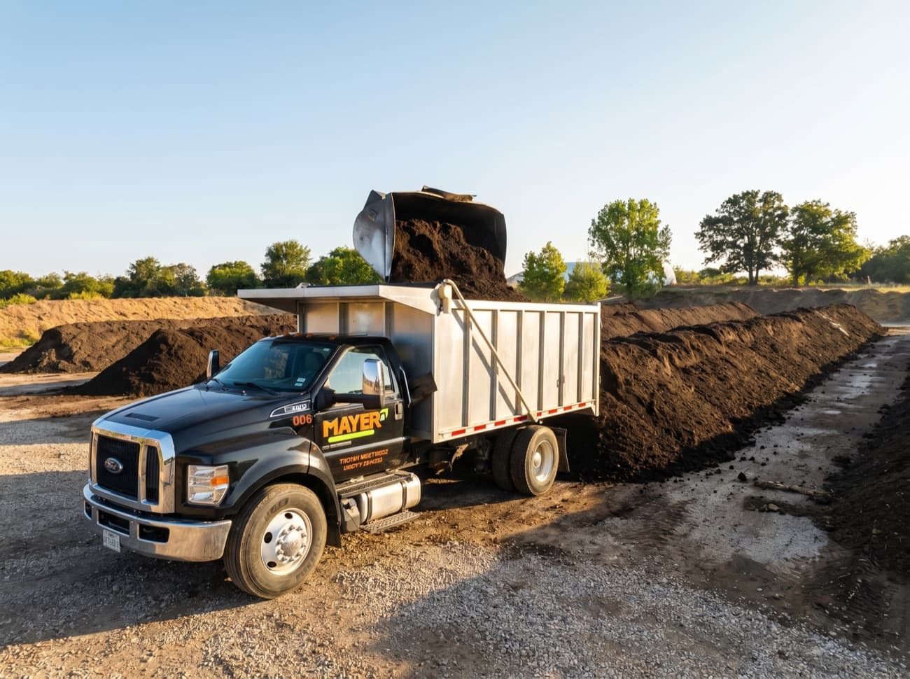 A Mayer Materials dump truck unloading fresh compost onto a windrow at the Azle facility